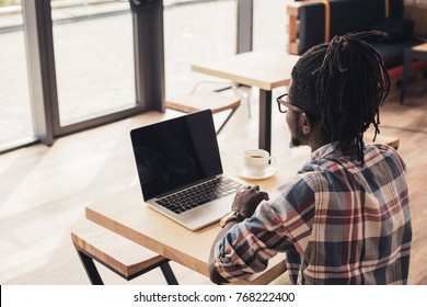 African American Man Using Laptop With Blank Screen In Coffee Shop