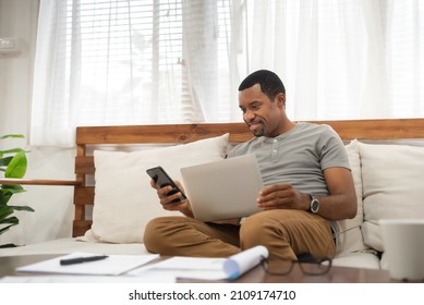 African American Man Using Smartphone At Home. Black Male Freelancer Texting On Mobile Phone In Living Room, Online Shopping.