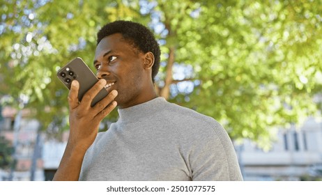 African american man using smartphone in sunlit park, portrait of connectivity and modern lifestyle outdoors. - Powered by Shutterstock