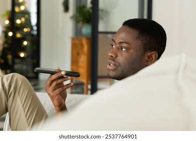 African American man using smartphone voice command at home during Christmas. technology, celebration, holiday, communication, voice recognition, winter - Powered by Shutterstock