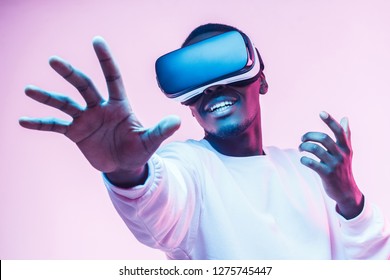 African american man in vr glasses, playing video games with virtual reality headset, trying to touch something with hand - Shutterstock ID 1275745447