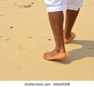 African american man walks on a sand beach. Close up of male feet and golden sand. Beach walk. Summer activity. Beautiful holiday background 