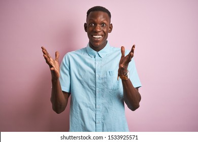 African American Man Wearing Blue Casual Shirt Standing Over Isolated Pink Background Celebrating Crazy And Amazed For Success With Arms Raised And Open Eyes Screaming Excited. Winner Concept