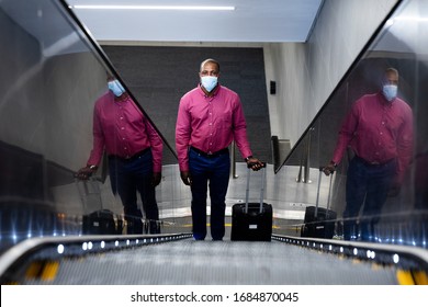 African American man wearing a face masks against air pollution and covid19 coronavirus, standing on escalator and holding a suitcase. - Powered by Shutterstock