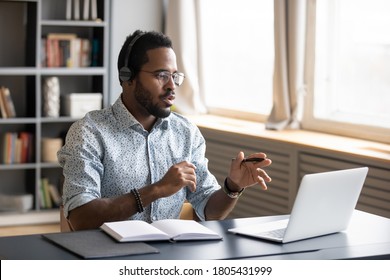 African American man wearing headphones speaking, using laptop, student wearing glasses learning language, watching video webinar or listening to lecture, mentor coach holding online lesson - Powered by Shutterstock