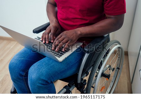 african american man in wheelchair with laptop at kichen