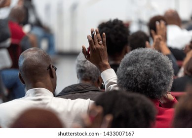 African American Man In A White Suit At Church With His Hand Raised