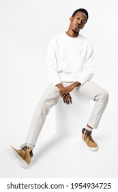 African American Man In White Sweater Sitting On A Chair Full Body