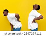 african american man in white t-shirt holding on to his back and bending over yellow isolated background, the concept of back pain and problems with the spine