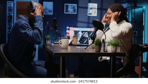 African american man and woman arriving together in apartment studio, ready to start recording podcast. Host inviting guest in living room used as broadcasting space to share stories - Powered by Shutterstock