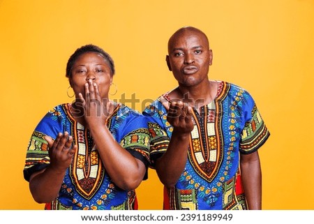African american man and woman couple sending air kiss together, sharing love and looking at camera. Romantic boyfriend and girlfriend pair showing affection studio portrait
