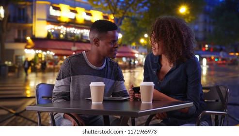 African American Man And Woman Drink Coffee And Use Smartphone On Paris Street