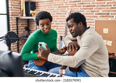 African American Man And Woman Music Group Using Smartphone Playing Ukelele At Music Studio