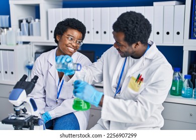 African american man and woman scientists measuring liquid at laboratory - Shutterstock ID 2256907299