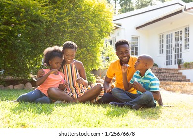 African American man and woman spending time with their son and daughter in their garden. Social distancing and self isolation in quarantine lockdown for Coronavirus Covid19