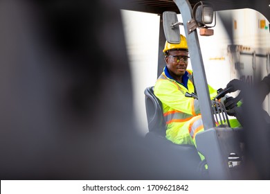 African American Man At Work. Professional Operation Engineering. Young Worker Forklift Driver Wearing Safety Goggles And Hard Hat Sitting In Vehicle In Warehouse