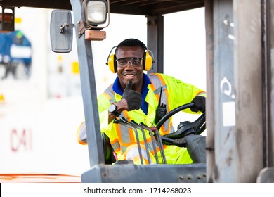 African American Man At Work. Professional Operation Engineering. Young Worker Forklift Driver Wearing Safety Goggles And Hard Hat Sitting In Vehicle In Warehouse