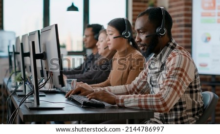 African american man working at call center office to help people with telemarketing assistance. Male employee using headphones and microphone at customer care service. Tripod shot.