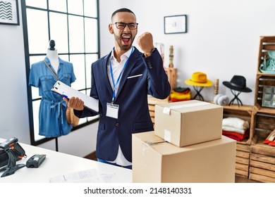 African American man working as a manager at retail boutique angry and raising fist frustrated and furious while shouting with anger. rage and aggressive concept. 