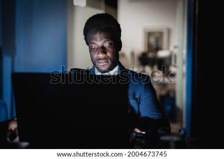 African american man working at night time inside modern office - Focus on face