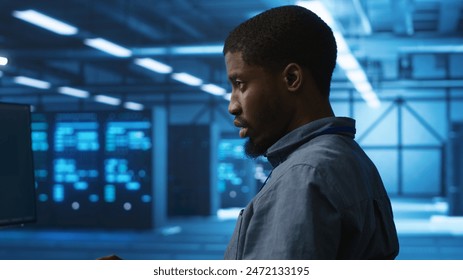 African american man working in server hub capable of processing vast amounts of data. IT programmer at PC desk typing on keyboard, updating servers controlling network resources, close up shot