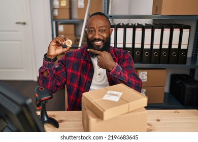 African American Man Working At Small Business Ecommerce Holding Bitcoin Smiling Happy Pointing With Hand And Finger 