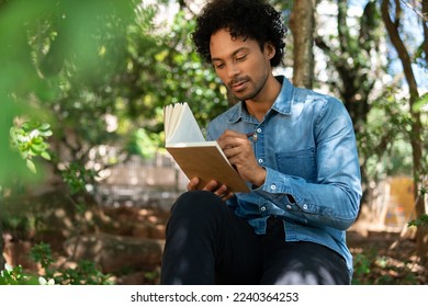 african american man writing in notebook ideas and enjoying nature in the park - Powered by Shutterstock