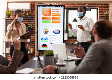 African american managers showing marketing presentation explaining business graphs working at company partnership in startup office. Businessteam with medical face mask against covid19 - Powered by Shutterstock