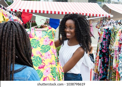 African american market vendor presenting clothes