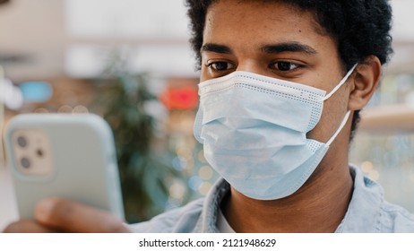 African American Masked Guy Man In Medical Mask Surprised Message Received Wins Online Bets Looking At Mobile Phone With Wide Open Eyes Surprise End Pandemic News Unexpected Good Result In Smartphone