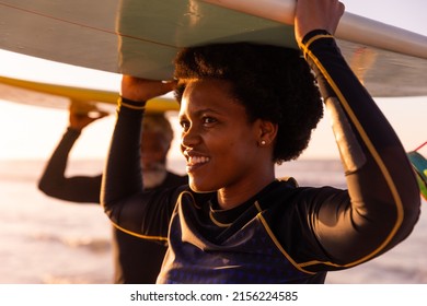 African american mature woman and senior man carrying surfboards on heads at beach at sunset. unaltered, love, togetherness, enjoyment, aquatic sport, holiday and active lifestyle concept. - Powered by Shutterstock