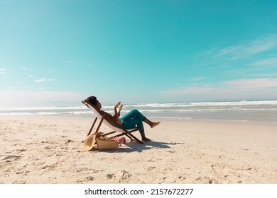 African american mature woman using digital tablet relaxing on deckchair at beach against sky. copy space, nature, summer, wireless technology, unaltered, lifestyle, enjoyment and holiday concept. - Powered by Shutterstock