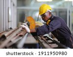 African American mechanic engineer worker is choosing copper tube for sawing while working in coolant factory with copy space