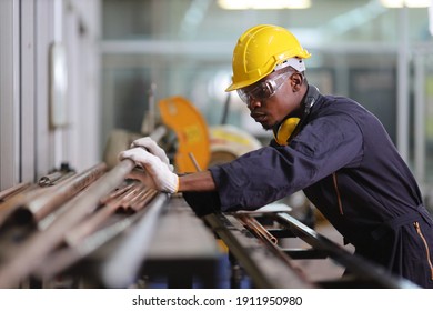 African American mechanic engineer worker is choosing copper tube for sawing while working in coolant factory with copy space