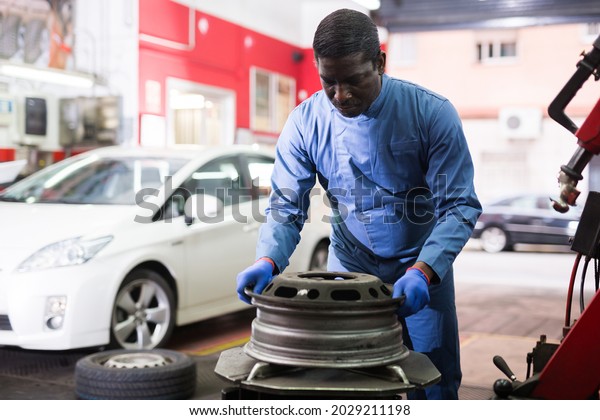 African\
american mechanic fixes car rims in a car\
service