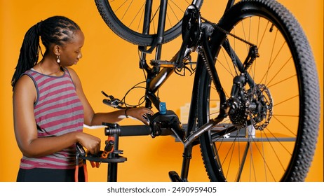 African american mechanic utilizing different tools to repair damaged bike handlebar grips, studio background. Employee using specialized gear to fix shifters and brake levers on bicycle, camera B - Powered by Shutterstock