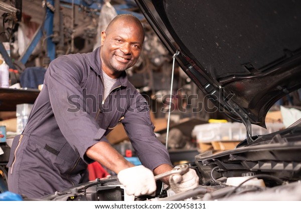 African american  mechanics - man\
examining car engine. Auto mechanic working in garage.Car Mechanic\
Detailed Vehicle Inspection. Auto Service Center\
Theme.