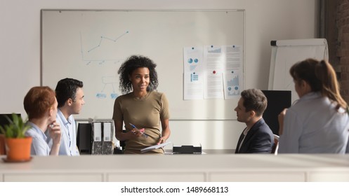 African American Millennial Female Team Leader Stand Holding Company Briefing Discussing Marketing Annual Plan With Colleagues, Black Young Businesswoman Brainstorm With Employees At Meeting