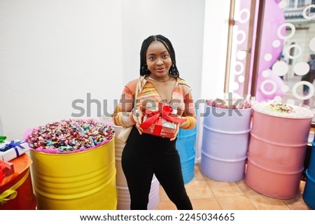 African american millennial lady at candy shop with present box of sweets.