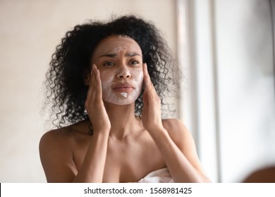 African American Millennial Woman Look In Mirror In Home Bathroom Apply Facial Moisturizing Cream Or Mask, Biracial Young Female Perform Morning Face Daily Routine Treatment, Beauty Procedure Concept