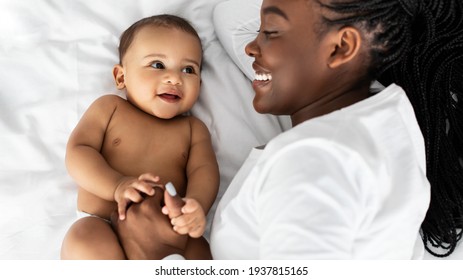 African American Mom Lying In Bed With Her Cute Baby