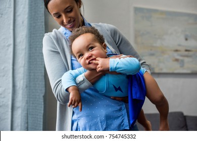 African American Mother And Baby Boy In Superhero Costume At Home