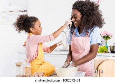 African American Mother And Daughter Having Fun While Making Dough On Kitchen