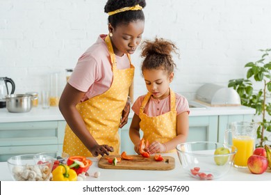 african american mother and daughter looking at bell pepper on cutting board - Powered by Shutterstock