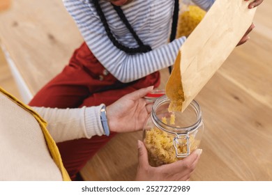 African american mother and daughter pouring pasta to glass jar in kitchen at home, copy space. Expression, togetherness, motherhood, childhood, food and drink and domestic life, - Powered by Shutterstock