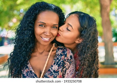 African american mother and daughter smiling happy hugging and kissing at the park.
