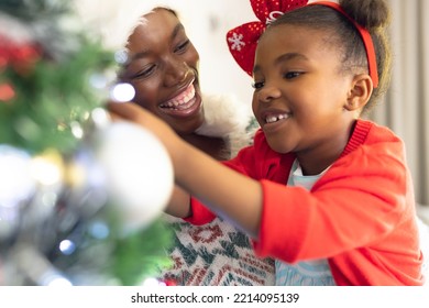 African american mother and daughter spending time together and decorating christmas tree. Christmas, family time and celebration concept. - Powered by Shutterstock