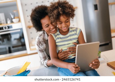 African american mother and daughter with tablet pc computer doing homework together at home - Powered by Shutterstock