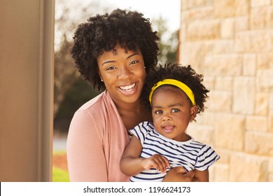 African American mother holding her daughter smiling.