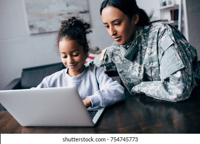 African American Mother In Military Uniform And Daughter Using Laptop At Home